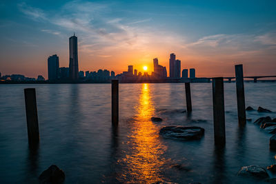 Scenic view of sea and buildings against sky during sunset