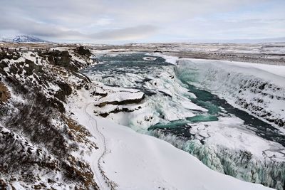 Scenic view of snowcapped waterfall against sky