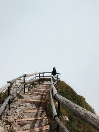 Low angle view of person on staircase against clear sky