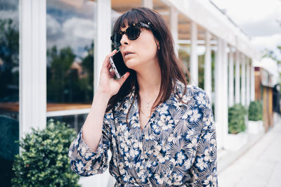 Beautiful young woman using mobile phone while standing outdoors