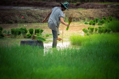 Full length of man standing on field by lake