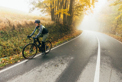 Rear view of man riding bicycle on road