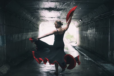 Rear view of woman dancing in tunnel