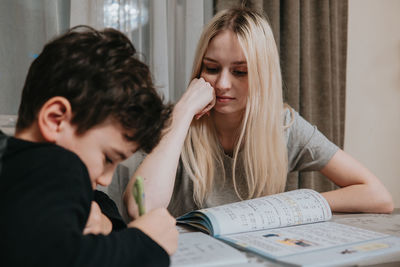 Mom and son are doing homework. sister helps brother solve math. home schooling. high quality photo