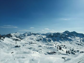 Scenic view of snowcapped mountains against blue sky