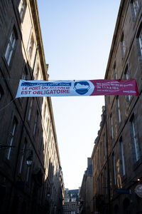 Low angle view of road sign against buildings in city