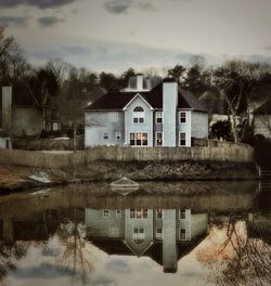 House by lake against sky