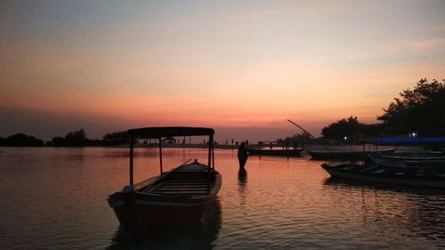 Silhouette boat moored on sea against sky during sunset