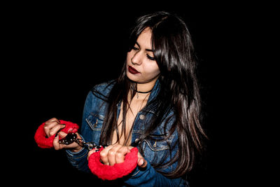 Portrait of young woman against black background