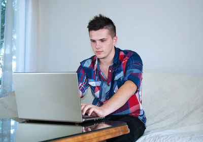 Teenage girl looking away while sitting on bed