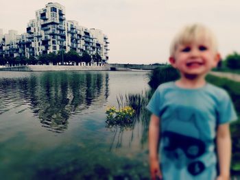 Portrait of smiling boy in city against sky