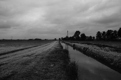 Canal amidst field against sky