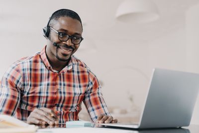 Side view of man using laptop while sitting on table