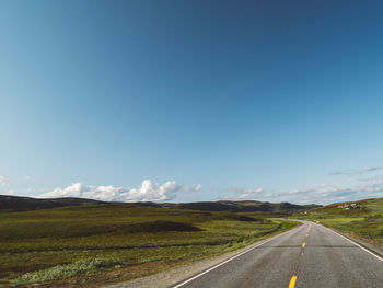 Empty road against clear blue sky