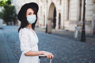 Portrait of woman wearing mask standing on street in city