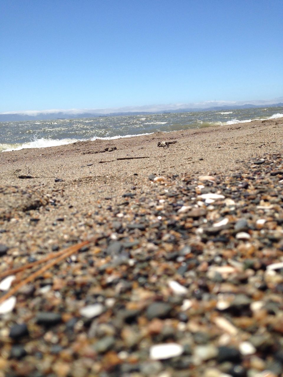 beach, clear sky, sea, sand, copy space, surface level, shore, horizon over water, blue, water, pebble, tranquility, tranquil scene, nature, scenics, stone - object, selective focus, beauty in nature, day, outdoors