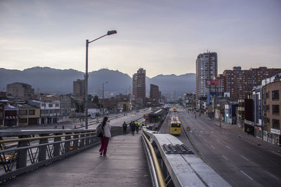 Woman walking on bridge against sky during sunset