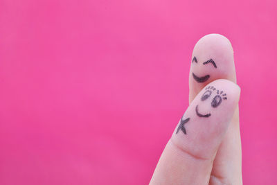 Cropped fingers with smiley faces against pink background