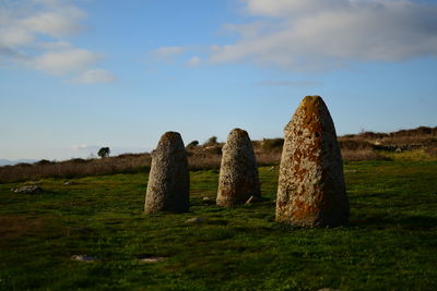 Ancient rock monuments on field against sky at sardinia