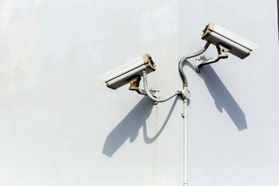 Low angle view of security camera on pole against sky