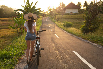 Rear view of man riding bicycle on road