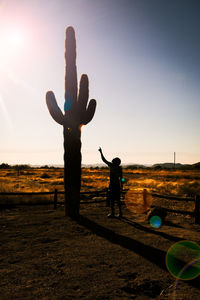 Silhouette person standing on field at sunset