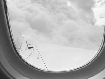 Close-up of airplane wing against cloudy sky