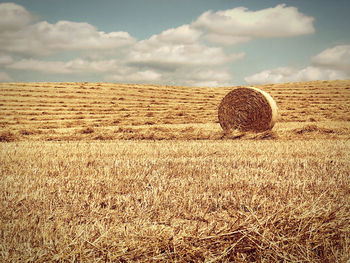 Hay bales on field against sky