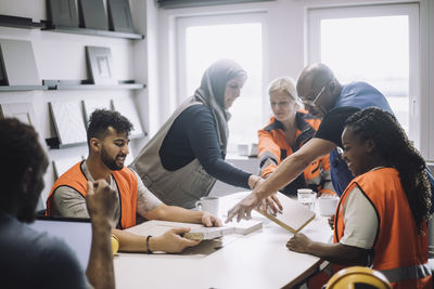 Male and female colleagues discussing together during meeting in warehouse office