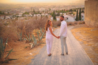 Portrait of happy young couple standing on road at hill