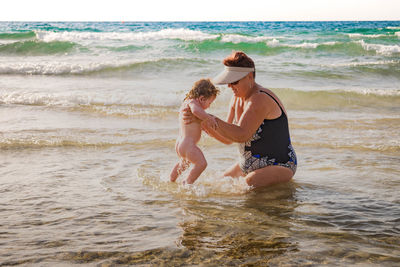 Woman with baby standing in sea