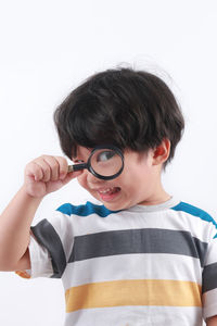 Portrait of boy holding eyeglasses against white background