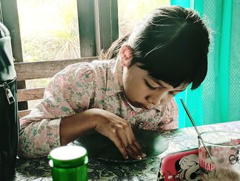 Rear view of girl looking at table