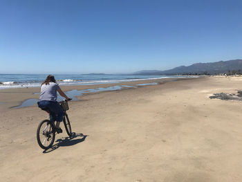 Senior woman  riding bicycle on beach