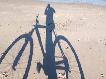 Shadow of man riding bicycle on sand