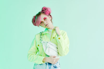 Portrait of smiling young woman standing against blue background