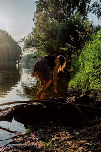 Woman by lake against trees in forest