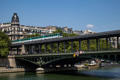 Bridge over river in city against sky