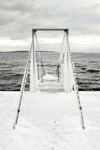 Pier on sea against cloudy sky