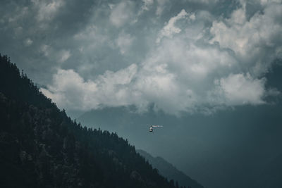 Helicopter flying through mountains against sky