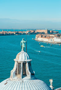 Statue in city against blue sea