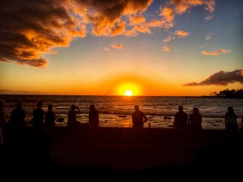 Silhouette people on beach against sky during sunset