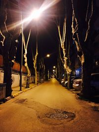 Empty road along illuminated street lights at night