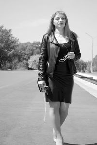 Portrait of young woman standing on road