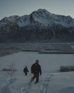 Rear view of people on snowcapped mountain against sky