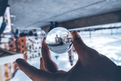 Midsection of person holding crystal ball with reflection of glass