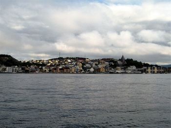 River in town against cloudy sky