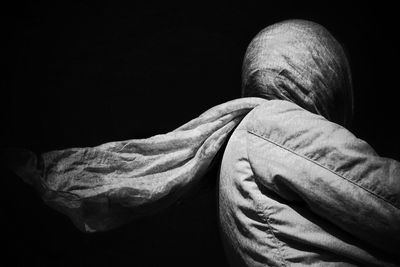 Low angle view of person wearing headscarf against black background