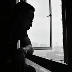 Side view of man looking through window