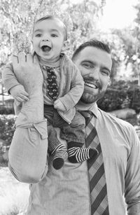 Close-up of happy man carrying cheerful son on shoulders at park